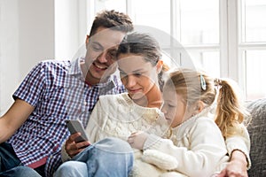 Parents with daughter watching video on mobile phone at home