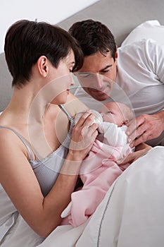 Parents Feeding Newborn Baby In Bed