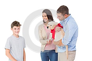 Parents gifting puppy to boy against white background