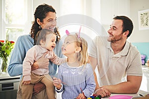 Parents, girl children and bunny ears in family home with funny face, baby or happiness for easter. Man, woman and kids