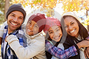 Parents Giving Children Piggyback Ride On Walk In Woods