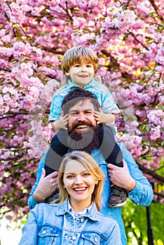 Parents giving piggyback ride to child. Happy family outdoors. Mother father and son. Portrait of family fun outside