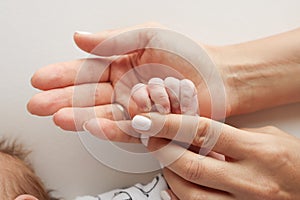 Parents& x27; hands hold the fingers of a newborn baby Family health and medical care