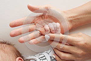 Parents& x27; hands hold the fingers of a newborn baby Family health and medical care
