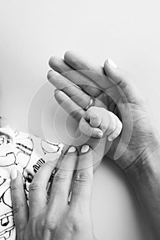 Parents' hands hold the fingers of a newborn baby. The hand of mother and father