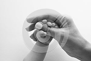 Parents& x27; hands hold the fingers of a newborn baby. Tiny fingers in black white