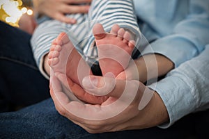 Parents& x27; hands hold the little child& x27;s feet