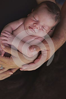 Parents hands hold small baby