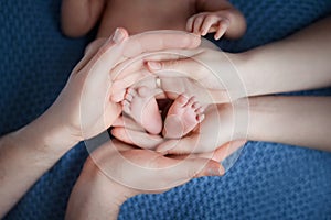 Parents hands hold in their hands the legs of their child on a white background, parental love and tenderness