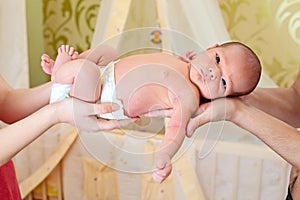 Parents' hands holding newborn baby boy