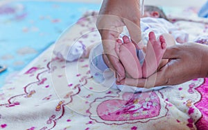 Parents hands holding small newborn baby girl feet