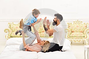Parents with happy faces pay attention to kid, play, clap hands. Mother and father cuddling with cute son. Young family