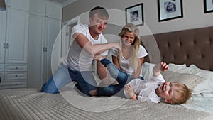 Parents having fun with their little daughter on bed. Family spending time at the morning