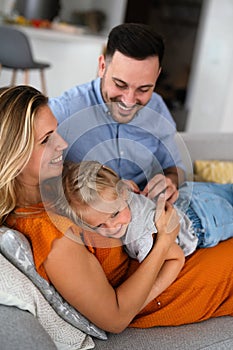 Parents having fun with their little daughter on bed. Family spending time at the morning.