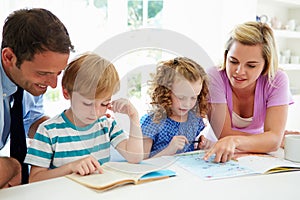 Parents Helping Children With Homework In Kitchen