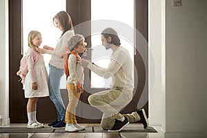 Parents helping children preparing go to school standing at hall