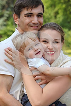 Parents hold child on hands in summer