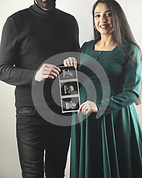 parents hold ultrasound picture of baby