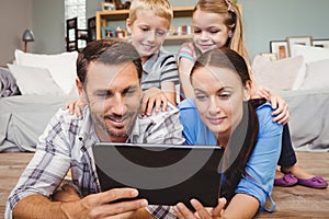 Parents holding digital tablet while kids sitting on their back