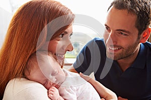 Parents At Home With Sleeping Newborn Baby Daughter