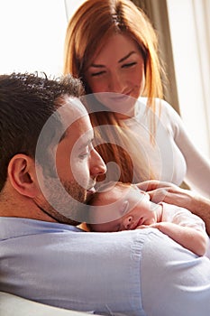 Parents At Home With Sleeping Newborn Baby Daughter