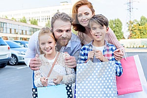 parents hugging children with shopping bags standing on street