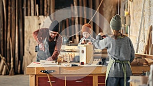 Parents and kid making  wooden bird house in craft workplace