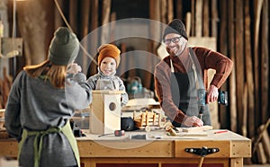 Parents and kid making  wooden bird house in craft workplace