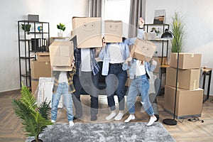 Parents and kids with boxes on heads standing at new house