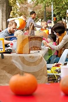 Parents And Kids Carve Pumpkins In A Public Park