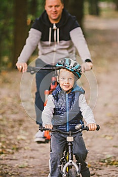 Parents and kids cycling on forest trail. family in warm clothes cycling autumn park. Family mountain bike on forest. active