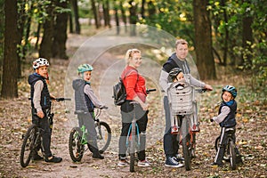 Parents and kids cycling on forest trail. family in warm clothes cycling autumn park. Family mountain bike on forest. active