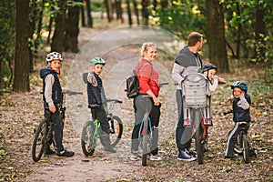 Parents and kids cycling on forest trail. family in warm clothes cycling autumn park. Family mountain bike on forest. active