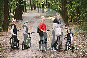 Parents and kids cycling on forest trail. family in warm clothes cycling autumn park. Family mountain bike on forest. active