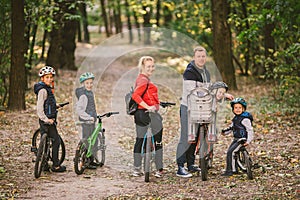 Parents and kids cycling on forest trail. family in warm clothes cycling autumn park. Family mountain bike on forest. active