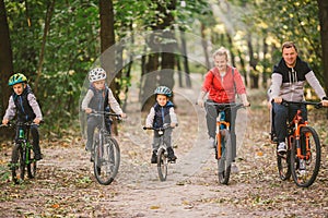 Parents and kids cycling on forest trail. family in warm clothes cycling autumn park. Family mountain bike on forest. active