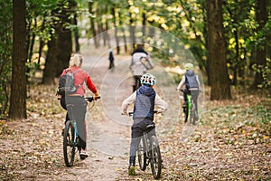 Parents and kids cycling on forest trail. Young family cycling in autumn park. Family mountain biking on forest. Theme family