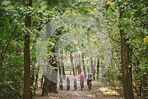 Parents and kids cycling on forest trail. Young family cycling in autumn park. Family mountain biking on forest. Theme family