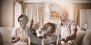 Parents and kids having fun while watching television in living room