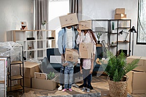 Parents with kids standing at new flat with boxes on heads