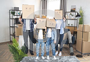 Parents with kids standing at new flat with boxes on heads