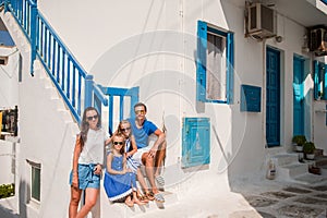 Parents and kids at street of typical greek traditional village on Mykonos Island, in Greece
