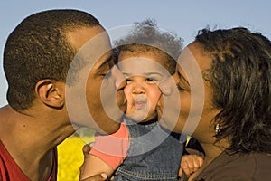 Parents kissing their baby