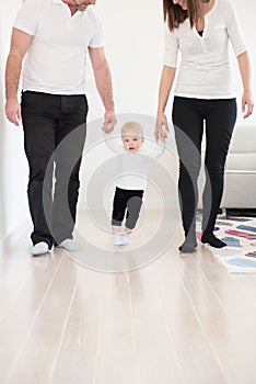 Parents learning their beautiful baby girl how to walk.