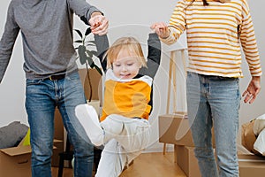 Parents lift up the child, holding hands.