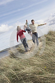 Parents lifting daughter (5-6) on sand dunes