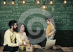 Parents listening their son, chalkboard on background. Homeschooling concept. Parents teaching kid at home. Boy