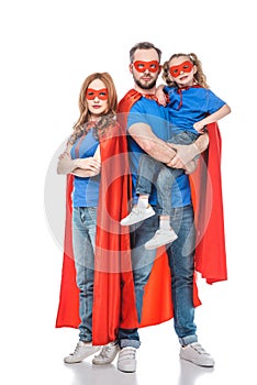 parents with little daughter pretending to be superheroes and looking at camera