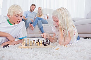 Parents looking at their children playing chess