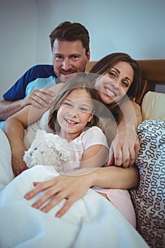 Parents lying on bed with daughter